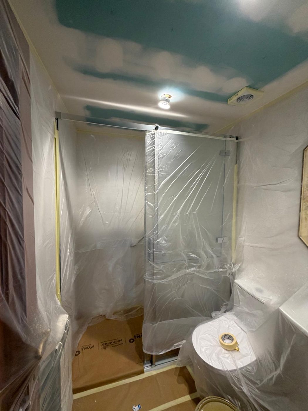 Baño con sanitarios y mampara totalmente protegidos durante la obra de pintura